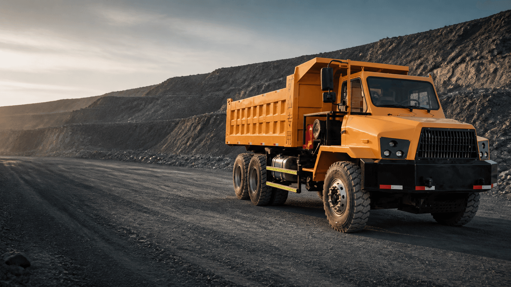 Yellow mining dump truck operating on a quarry haul road